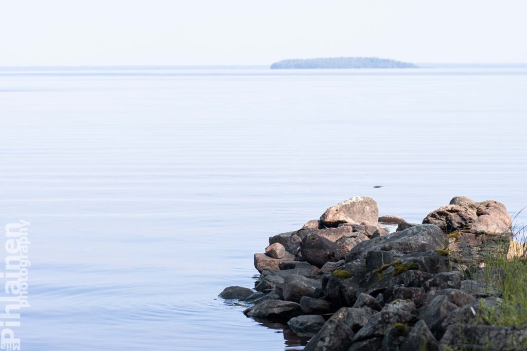 Etualalla kivistä tehtyä venevalkamaa Oulujärven rannassa. Horisontissa näkyy saari.