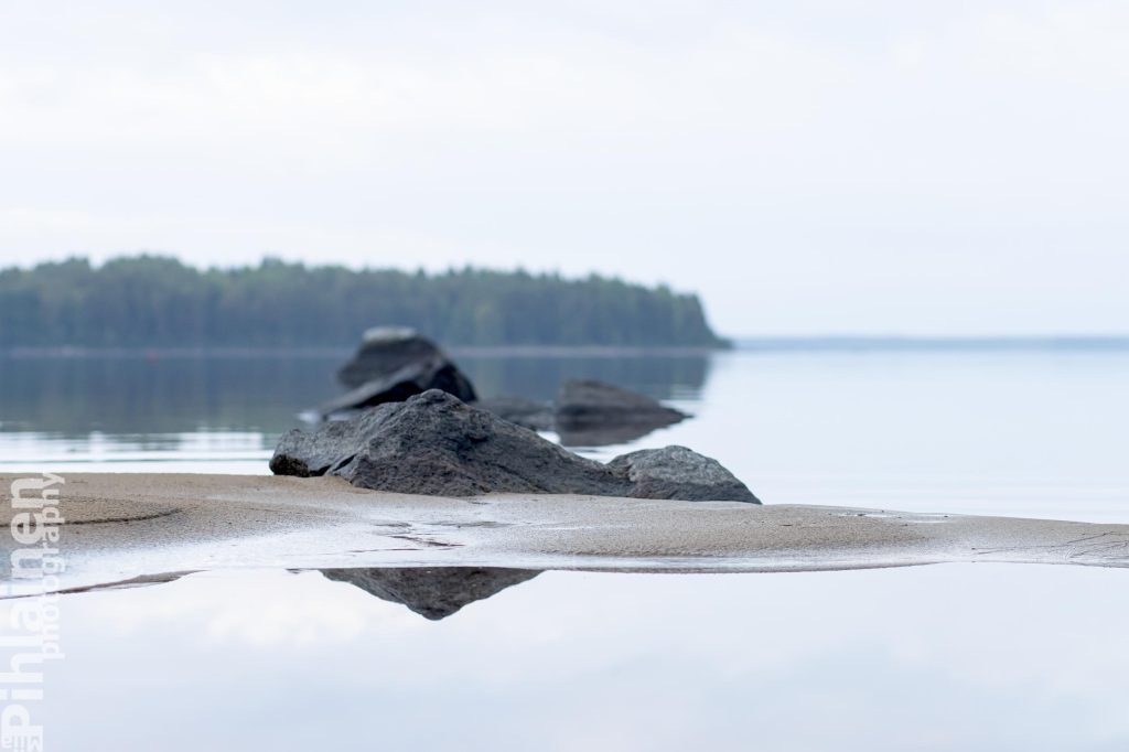 Tyyni Oulujärvi. Kuvassa näkyy etualalla hiekkasärkkä ja kiviä.
