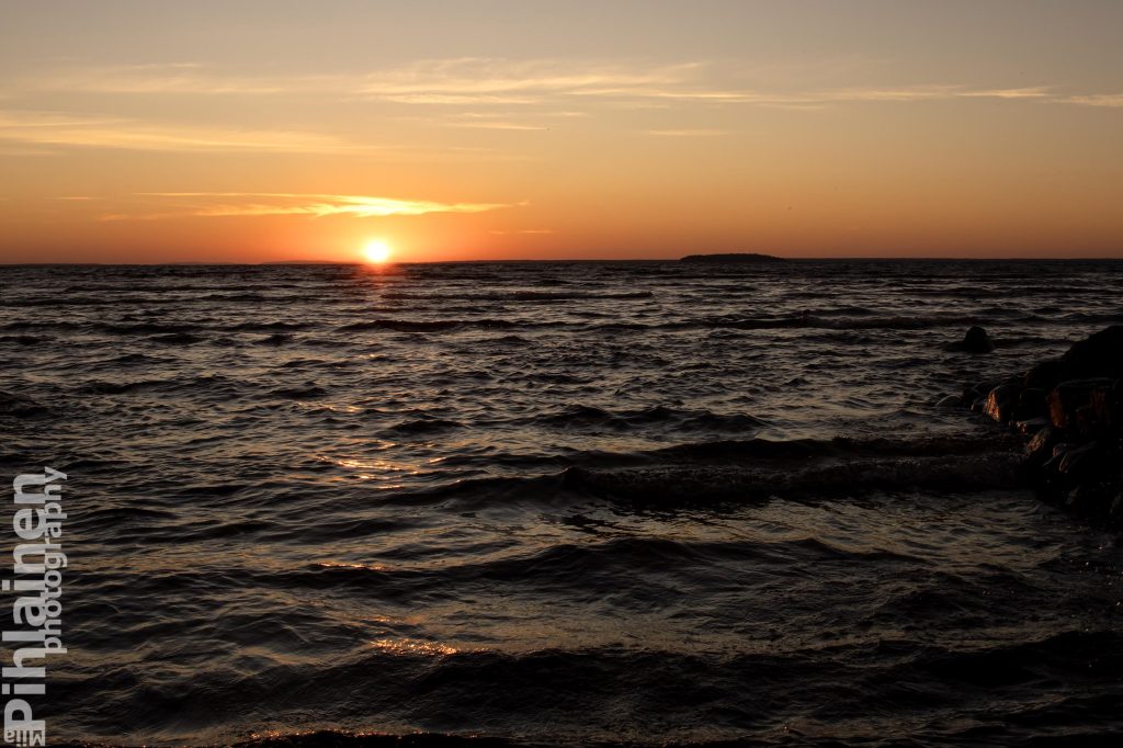 Auringonnousu Oulujärvellä. Aurinko on juuri nousemassa kokonaan horisontin yläpuolelle.
